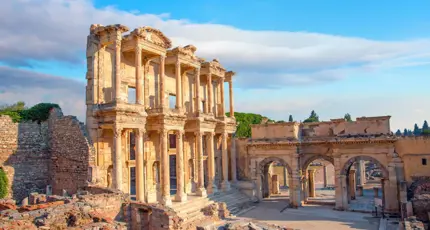Ancient ruins of the Library of Celsus in Ephesus, Turkey, with a clear sky and warm sunlight highlighting the detailed stone architecture