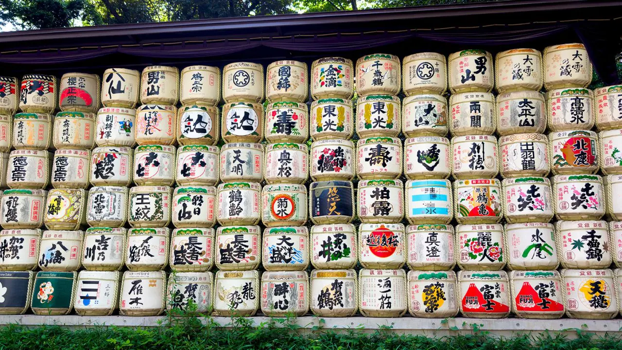 Rows of decorative sake barrels stacked outside the Meiji Shrine in Tokyo, Japan, featuring colourful Japanese calligraphy and traditional symbols