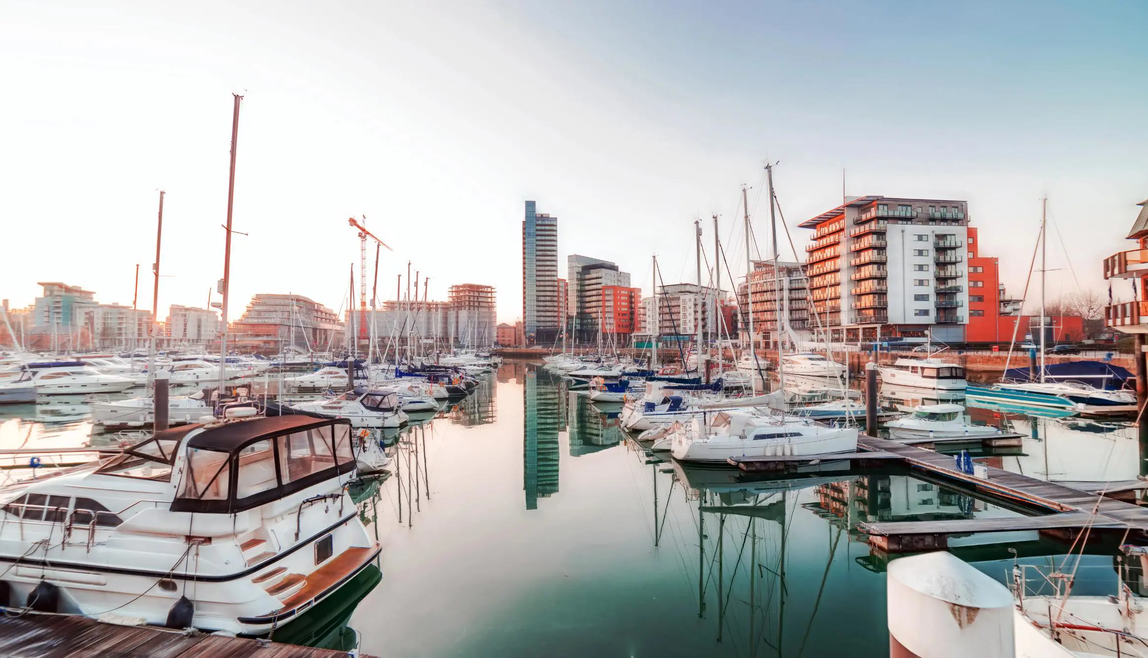 Ocean Village Marina in Southampton, featuring moored yachts and sailboats in calm water, with modern waterfront apartments and restaurants in the background