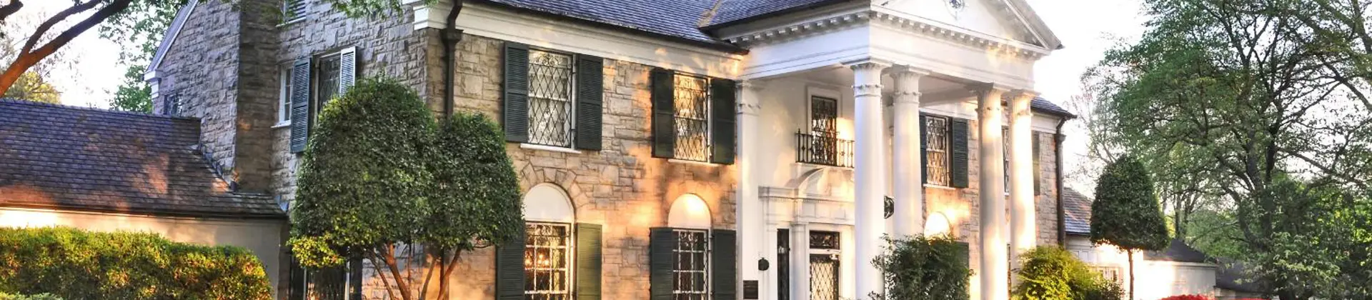 Graceland mansion in Memphis, Tennessee, the former home of Elvis Presley, featuring a grand white-columned façade surrounded by well-kept lawns and tall trees
