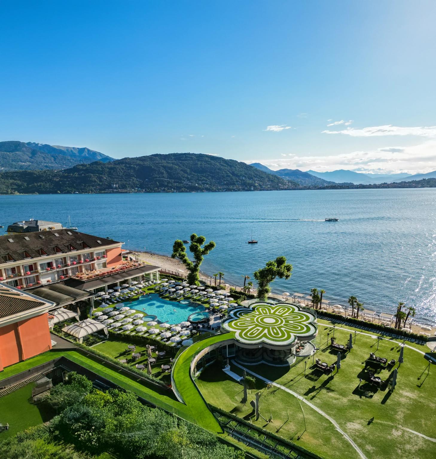 Aerial view of the lakeside pool and gardens at Grand Hotel Dino in Baveno, with Lake Maggiore and mountains in the background