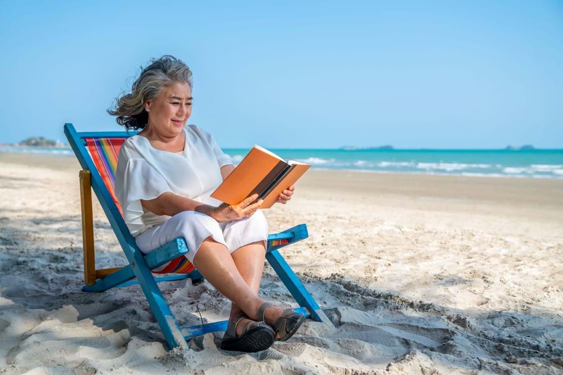 Woman Reading Book on Beach