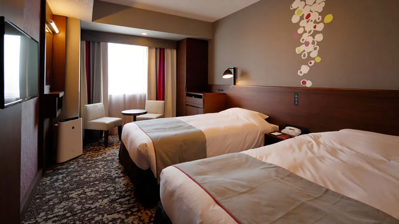 Comfortable standard twin room at Hotel Monte Hermana with two single beds, rich wood accents, patterned carpet, and seating by the window