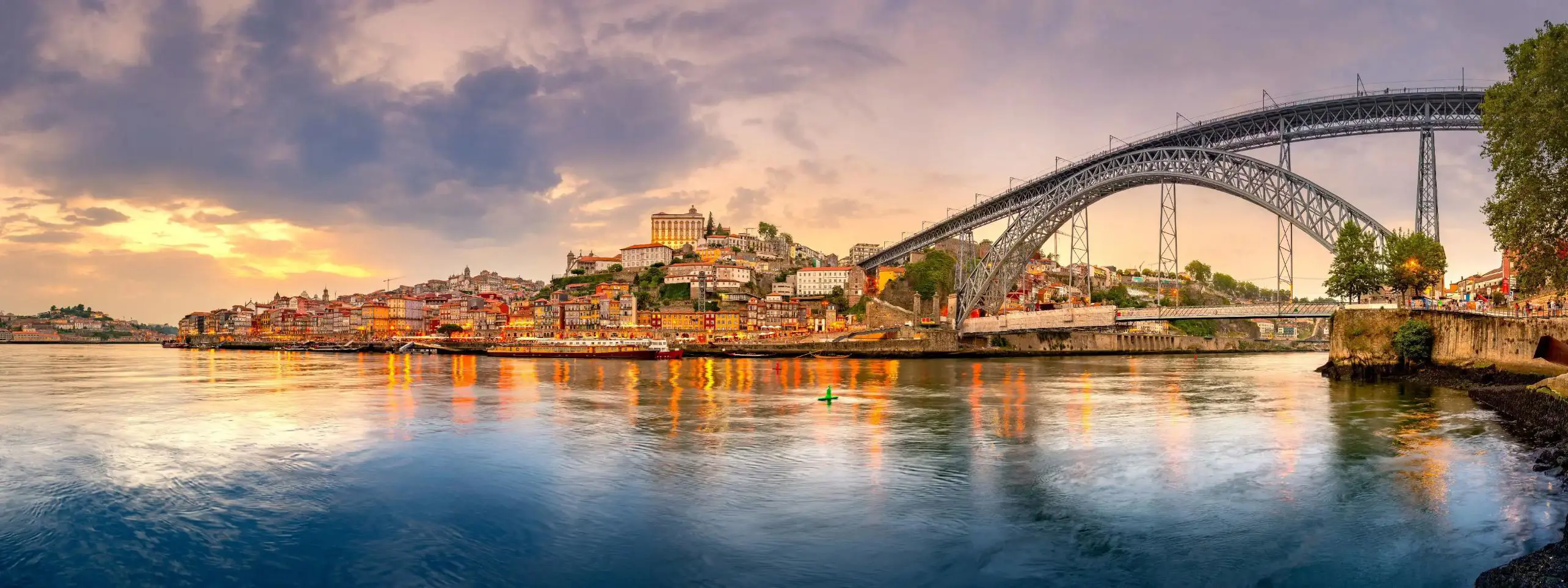 Picturesque view of Porto, Portugal, showing the Dom Luís I Bridge crossing the Douro River, with historic, colourful buildings along the riverbanks
