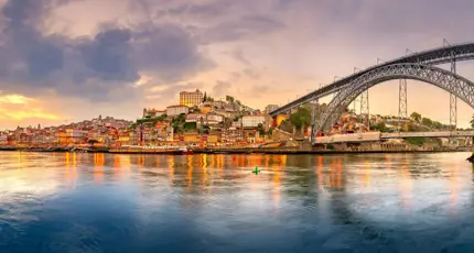 Picturesque view of Porto, Portugal, showing the Dom Luís I Bridge crossing the Douro River, with historic, colourful buildings along the riverbanks