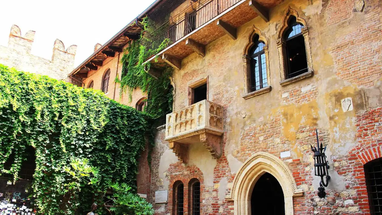 Juliet's Balcony on a brick and stucco building in Verona, Italy, with arched windows and doors, inspired by Shakespeare's Romeo and Juliet