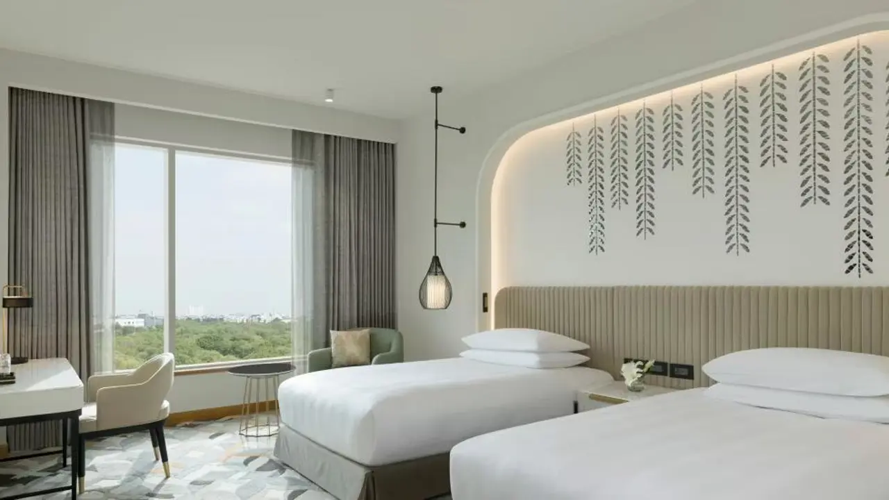 A modern hotel room with two single beds, soft lighting and a large window at the InterContinental in Jaipur