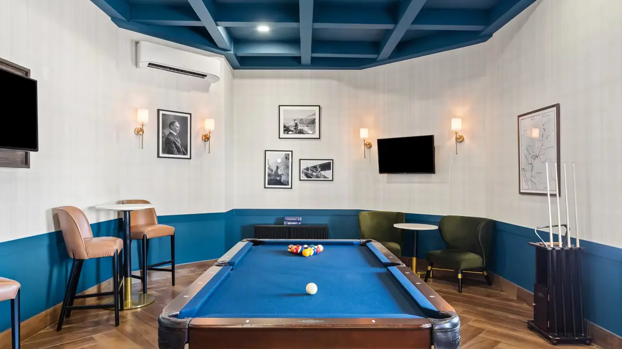 Interior of a cosy game room at The Ellsworth Hotel, featuring a pool table, arcade games, and comfortable seating, with warm lighting creating a fun and inviting atmosphere