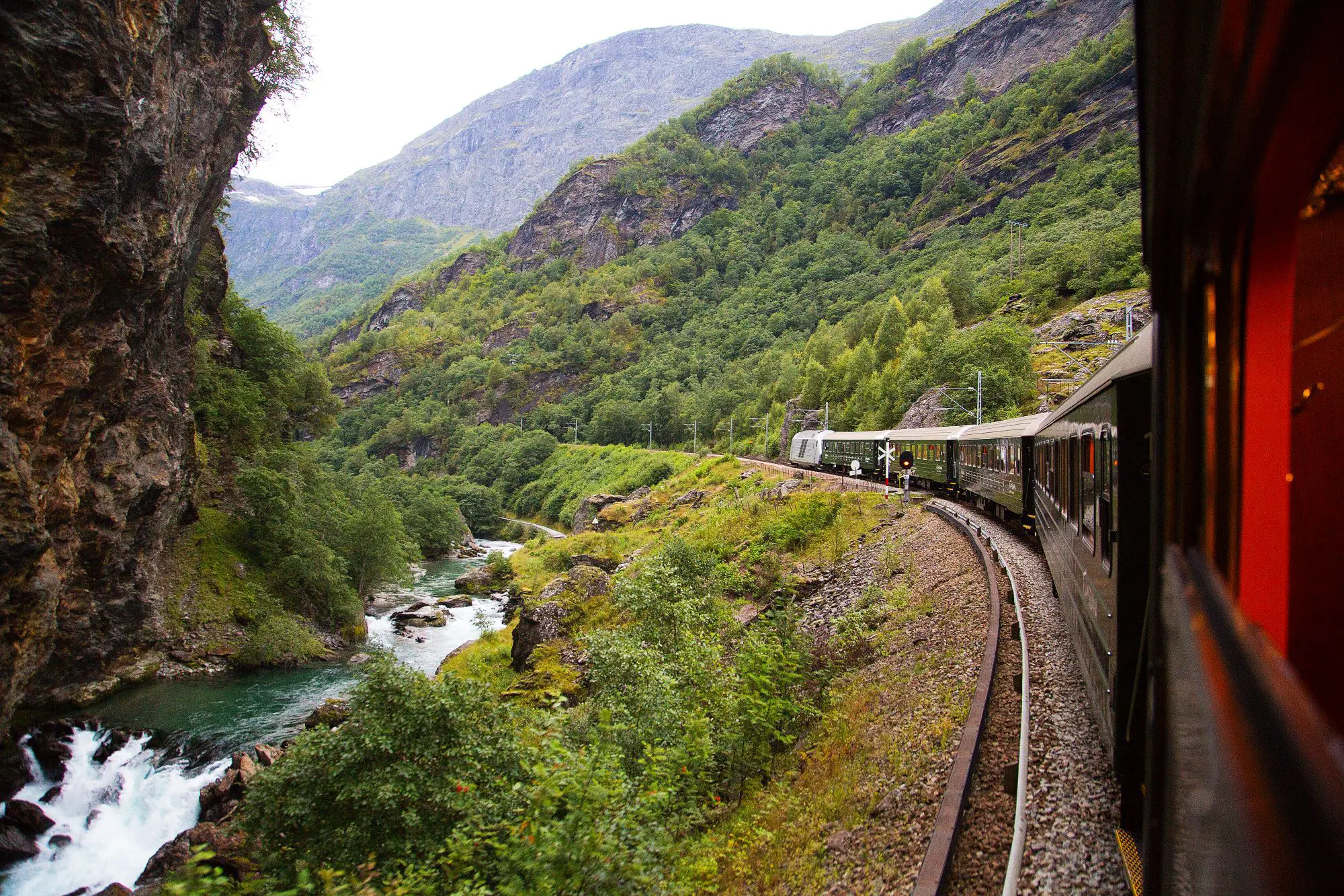 Train going through the mountains by a small stream of water