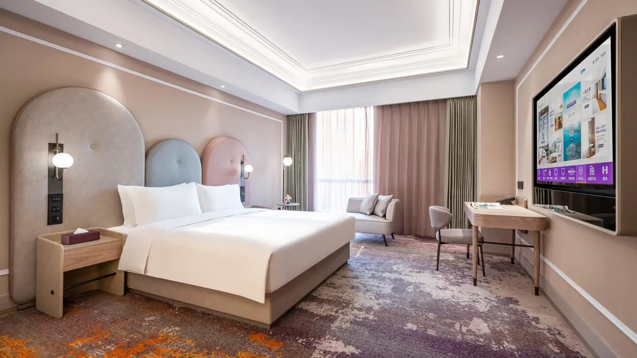 A stylish double room featuring a large bed, desk area and lounge seat next to the floor-to-ceiling window at the Mercure Beijing Downtown Hotel in Beijing, China