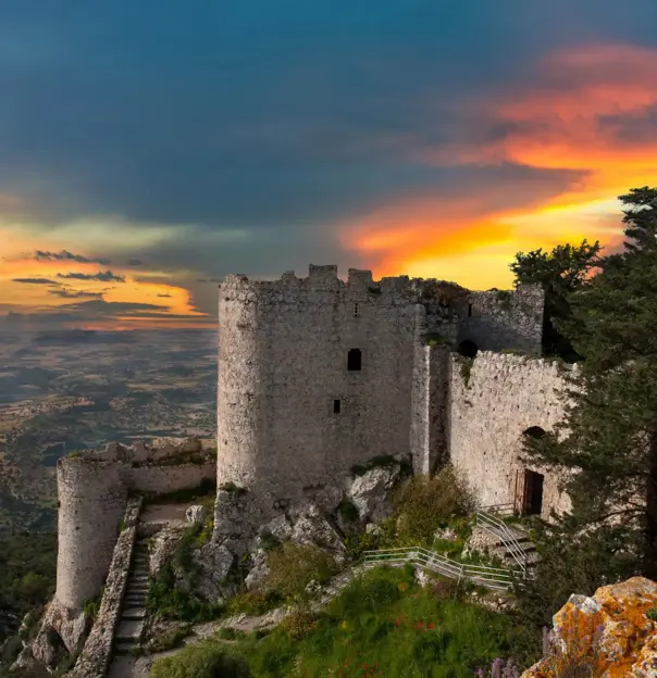Ancient stone castle ruins on a hilltop overlooking the landscape of Northern Cyprus at sunset