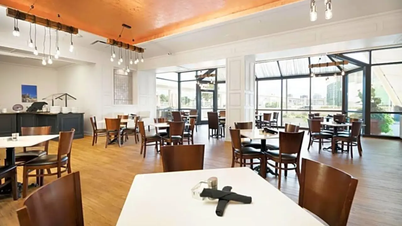 Breakfast area at Fort Pontchartrain hotel, featuring neatly arranged tables and chairs in a bright, spacious dining room with large windows letting in natural light