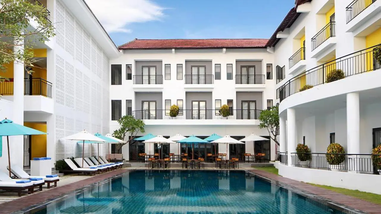 Exterior of Hotel ÊMM Hoi An featuring private balconies overlooking a swimming pool surrounded by sun loungers