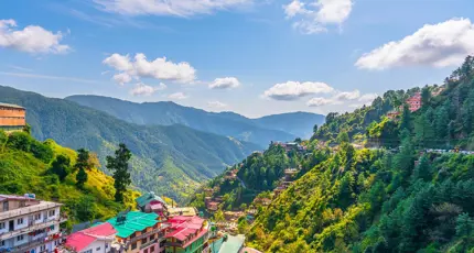 A panoramic view of Shimla’s colourful hillside buildings surrounded by lush green mountains and misty clouds in the Himalayan foothills