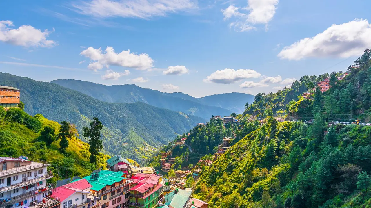 A panoramic view of Shimla’s colourful hillside buildings surrounded by lush green mountains and misty clouds in the Himalayan foothills