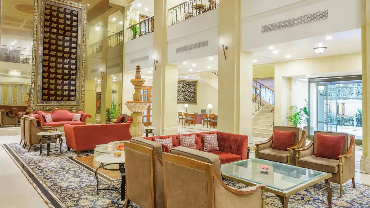 Radisson Hotel in Varanasi's elegant lobby with plush red and beige seating, ornate décor and a patterned rug beneath warm lighting