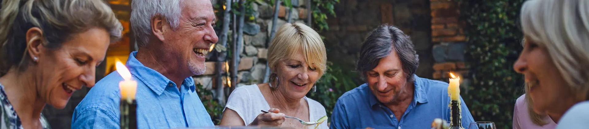 People around a table eating al fresco & sharing food by candlelight 