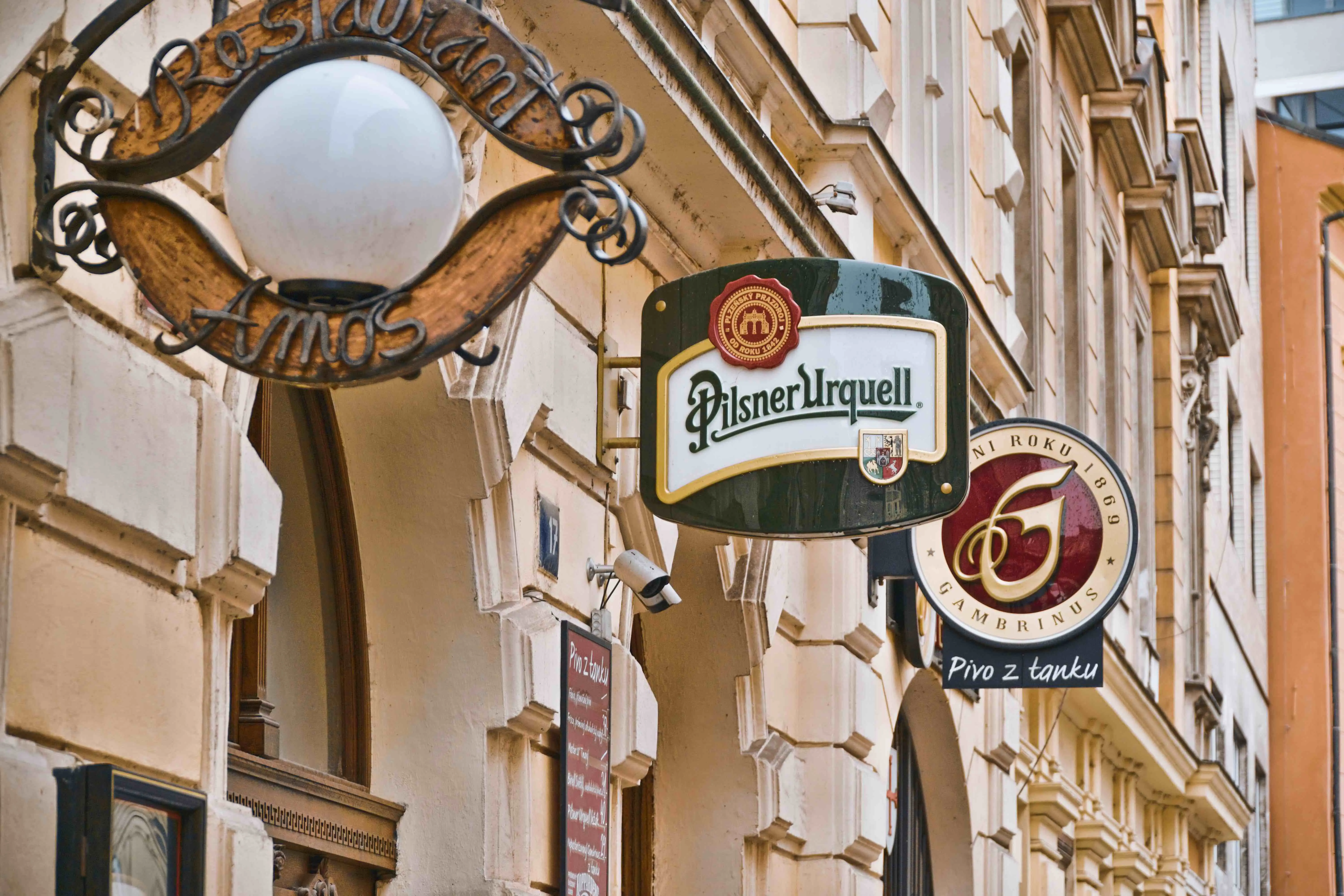 Horizontal extended signs attached to buildings in Prague, advertising a restaurant, and beers - Pilsner Urquell and Pivo z tanku