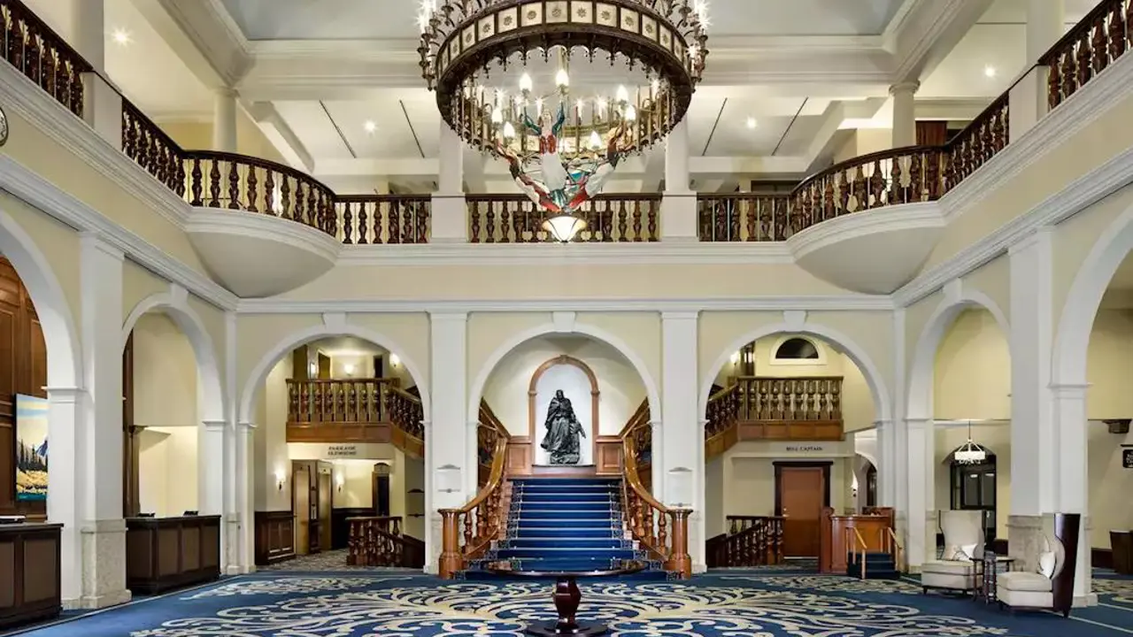 The grand lobby and entrance of Fairmont Chateau, Lake Louise featuring elegant blue and magnolia detailing, with classic furnishings and refined alpine charm