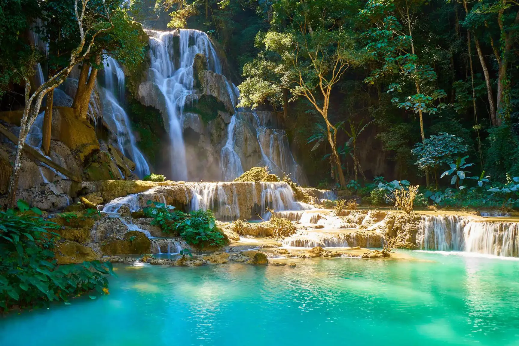 Kuang Si Falls in Laos, featuring turquoise limestone pools and cascading waterfalls framed by dense green jungle