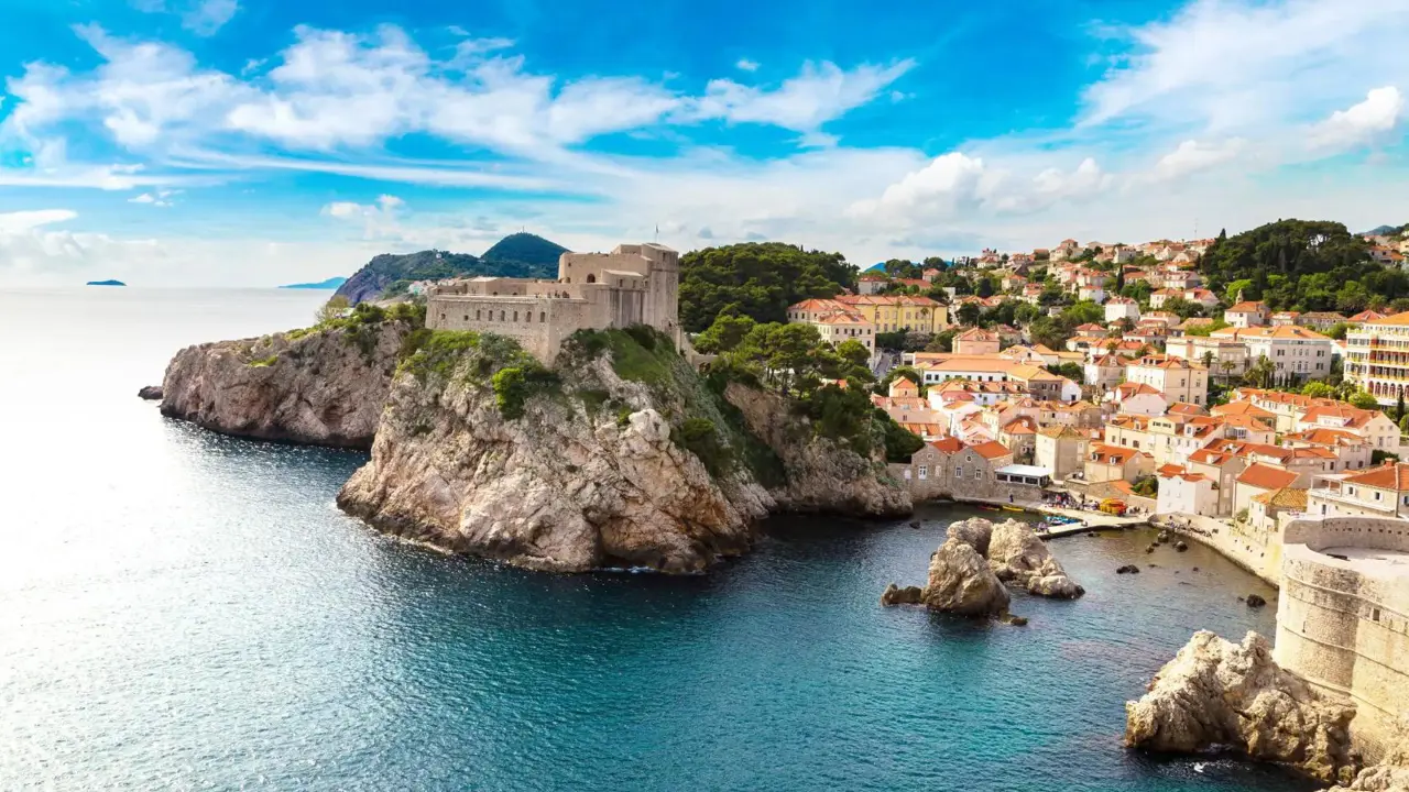 Panoramic view of the walled Old Town of Dubrovnik, Croatia, perched on a rocky coastline beside the blue waters of the Adriatic Sea