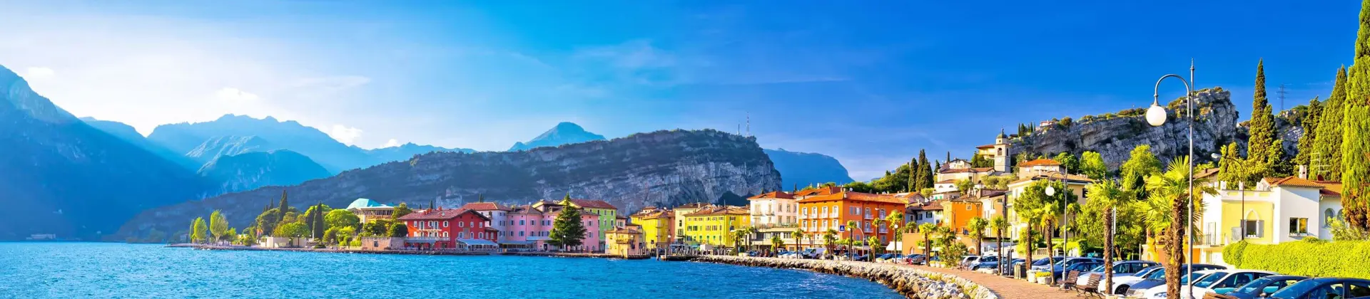 Waterfront in Torbole, Lake Garda, showing pavement and buildings and mountains in the distance
