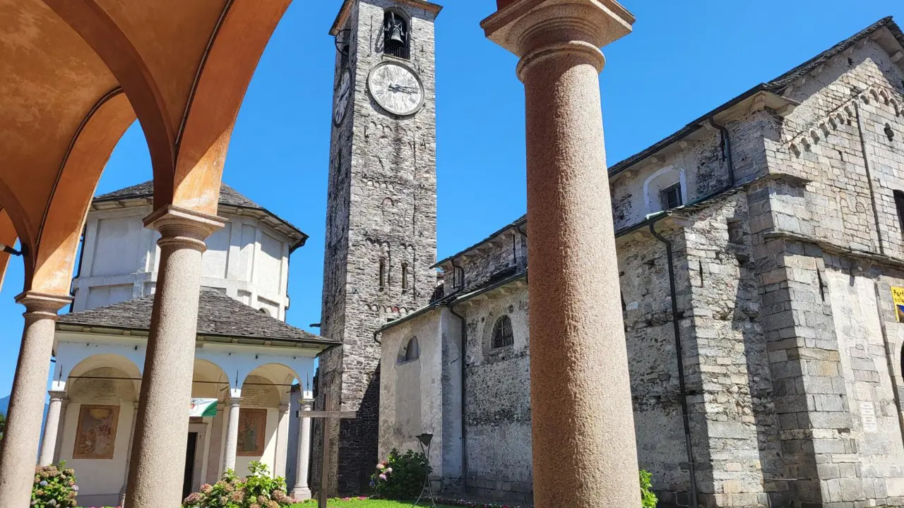 View of the Church of Gervasio and Protasio’s clock tower in Baveno, Italy, seen from under arches in the courtyard