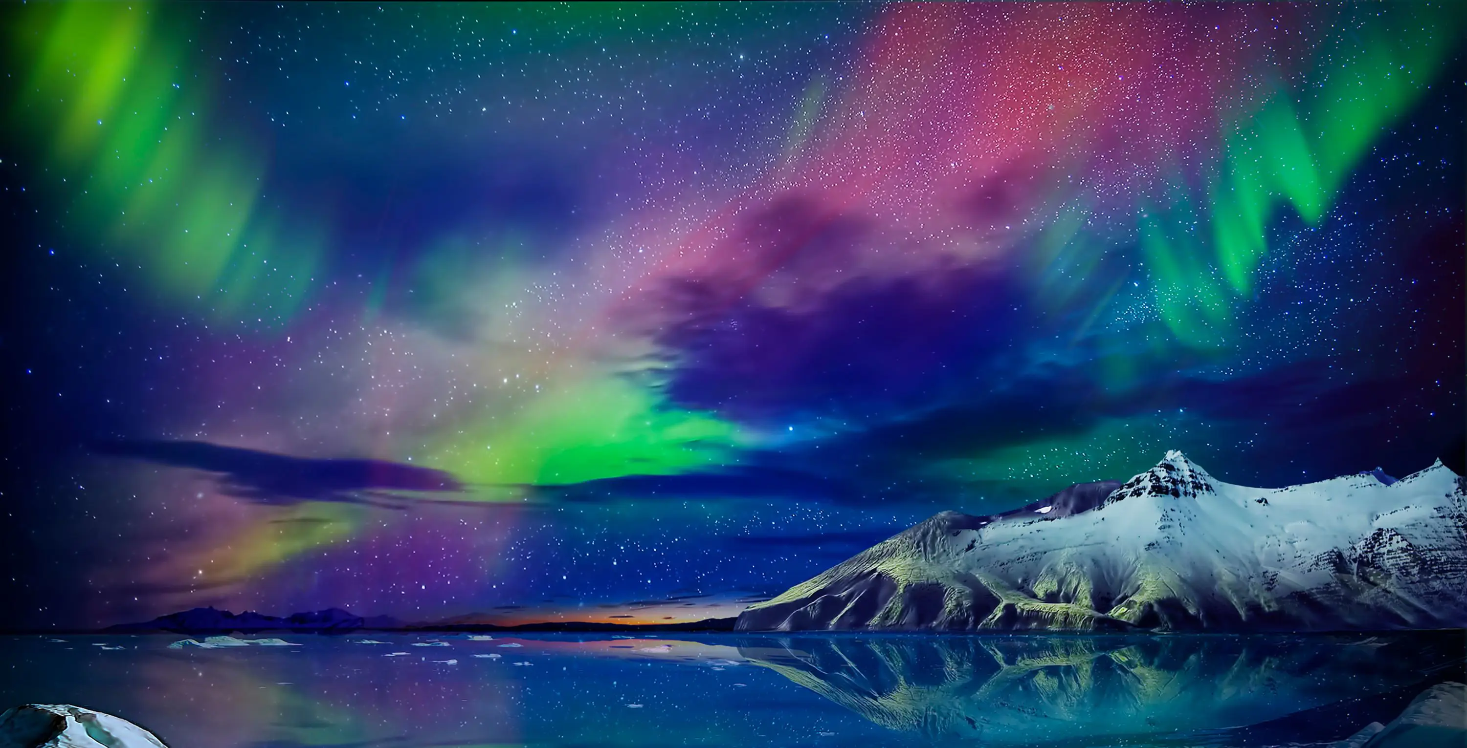 Starry sky with green, purple and blue Northern Lights. Below, a lake and a snowy mountain