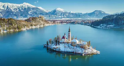 Lake Bled in winter with its island church in the centre and frosty mountains in the background