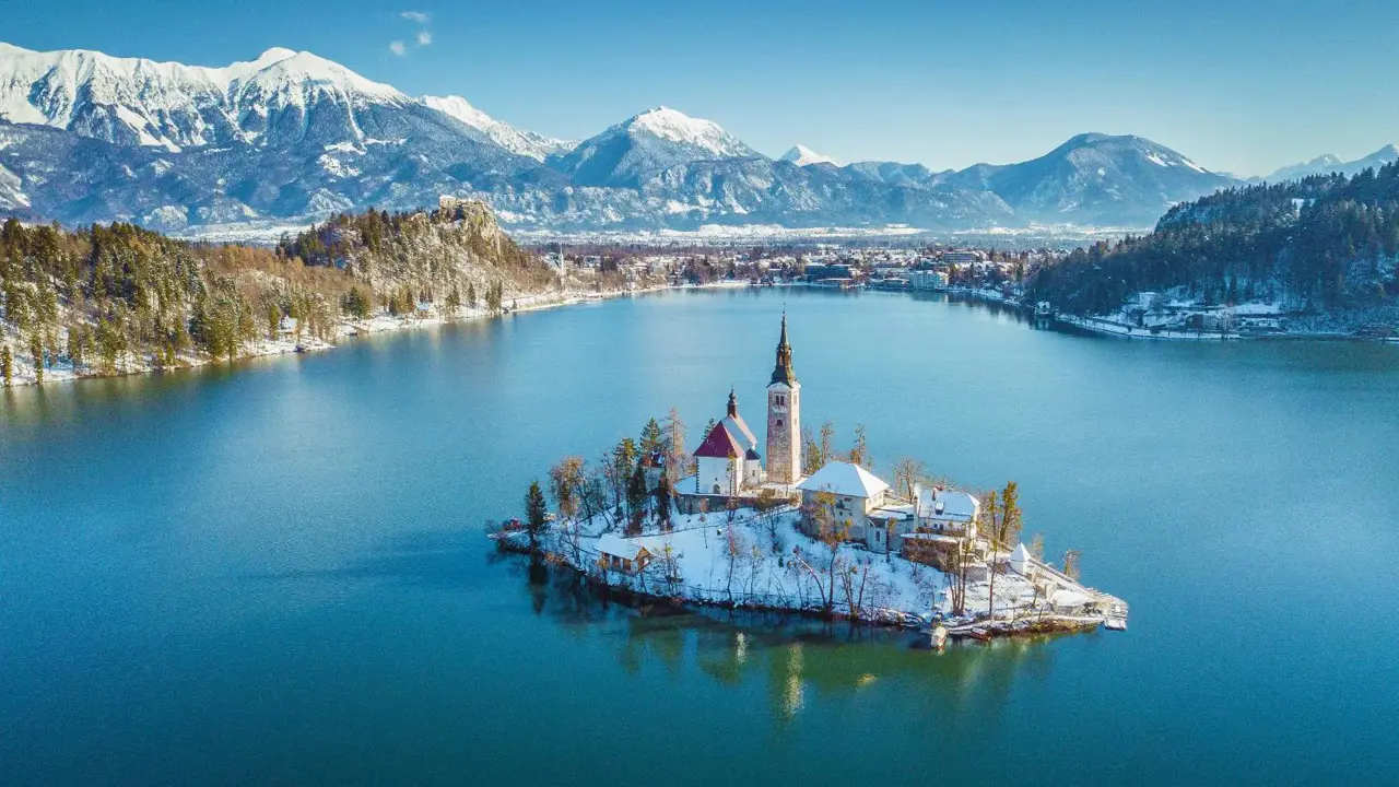 Lake Bled in winter with its island church in the centre and frosty mountains in the background