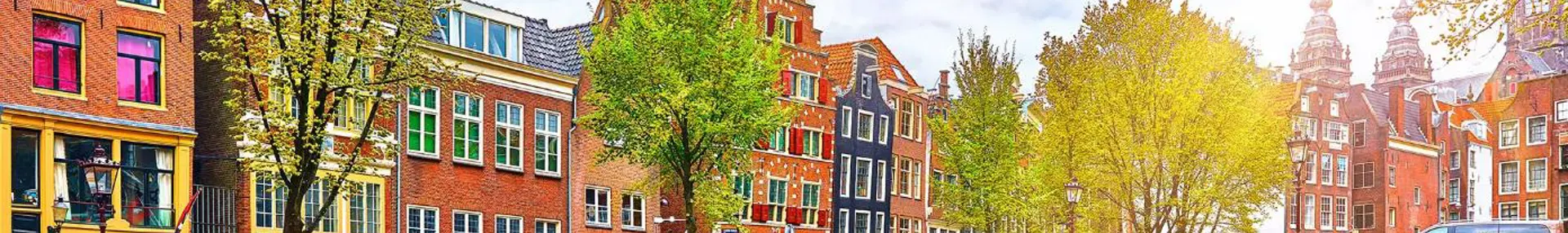 Scenic view of a canal in Amsterdam, Netherlands, with traditional Dutch buildings lining both sides